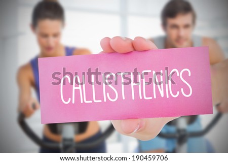 Woman holding pink card saying callisthenics against fitness class in gym