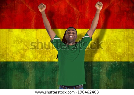 Cheering football fan in green jersey against ghana flag in grunge effect