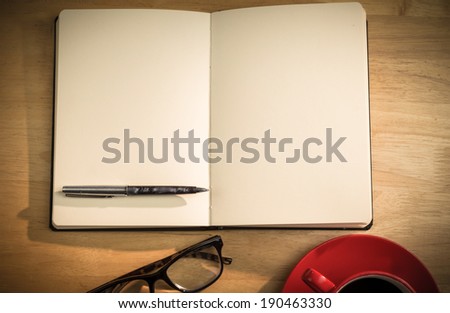 Overhead of notepad and pen and coffee on a desk
