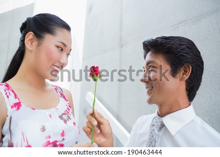 Man offering a red rose to girlfriend on the stairs