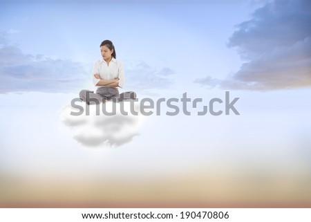 Grumpy businesswoman sitting cross legged against beautiful orange and blue sky
