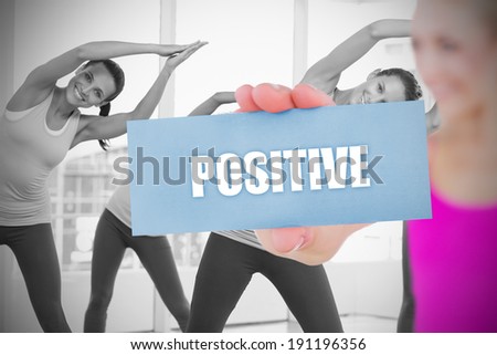 Fit blonde holding card saying positive against fitness class in gym