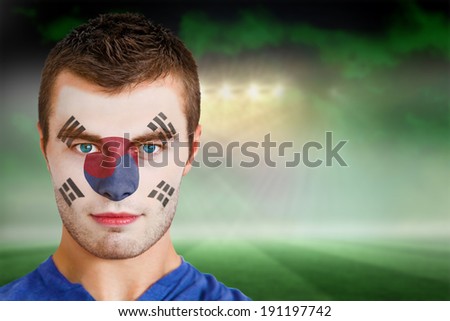Composite image of south korea football fan in face paint against football pitch under green sky and spotlights