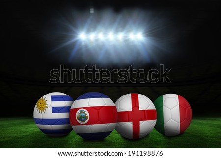 Composite image of footballs in group d colours for world cup against football pitch under spotlights