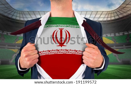 Businessman opening shirt to reveal iran flag against large football stadium with brasilian fans