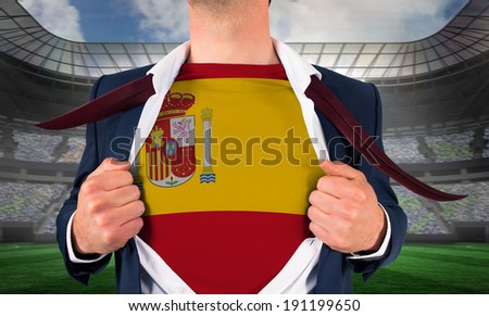 Businessman opening shirt to reveal spain flag against large football stadium under spotlights