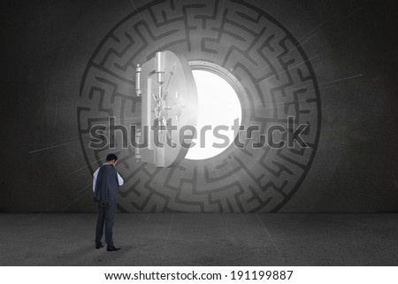 Businessman standing against open safe in middle of maze on black wall