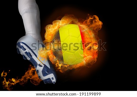 Football player kicking flaming belgium ball against black