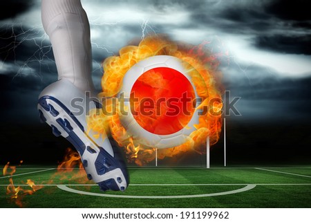Football player kicking flaming japan flag ball against football pitch under stormy sky