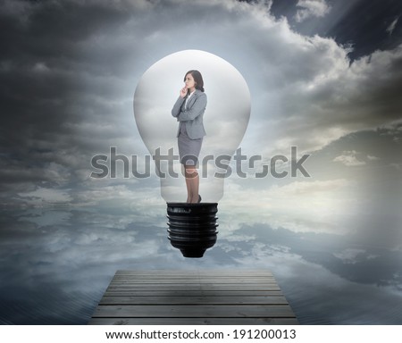 Thinking businesswoman in light bulb against bridge over peaceful water