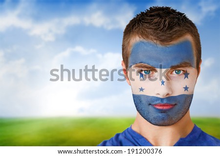 Composite image of honduras football fan in face paint against football pitch under blue sky