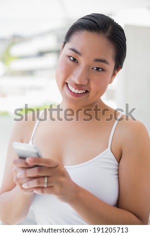 Asian woman texting on phone outside on a balcony