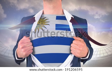 Businessman opening shirt to reveal uruguay flag against large football stadium under cloudy blue sky