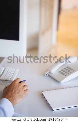 Casual businessman at desk with notepad and telephone in his office