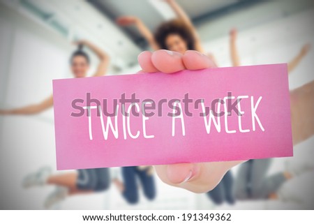 Woman holding pink card saying twice a week against fitness class in gym