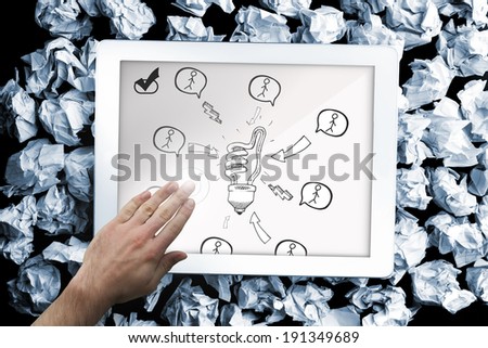 Composite image of hand touching tablet showing light bulb doodle with stick figures