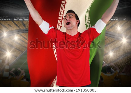Excited football fan cheering holding iran flag against vast football stadium with fans in yellow