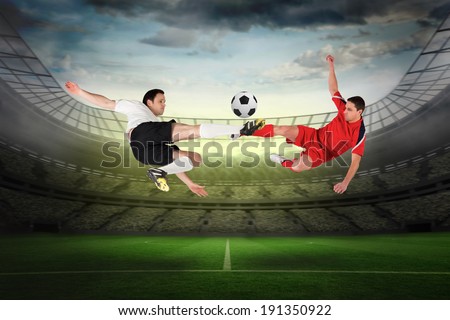 Football players tackling for the ball against large football stadium with lights