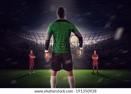 Composite image of goalie facing opposition against large football stadium with fans in yellow