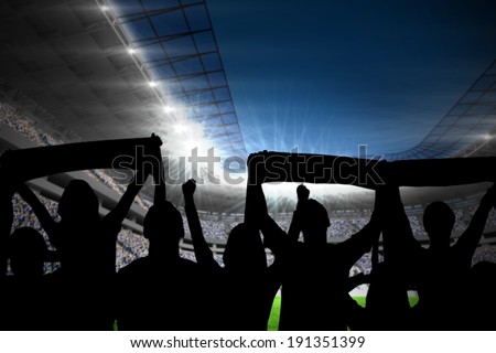 Silhouettes of football supporters against football stadium