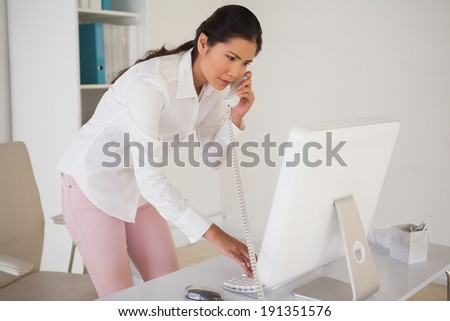 Casual businesswoman answering the phone in her office