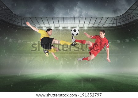 Football players tackling for the ball against misty football stadium under spotlights