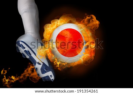 Football player kicking flaming japan ball against black