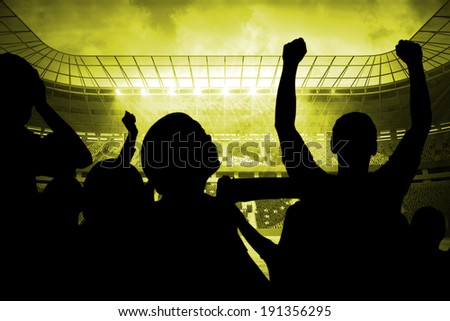 Silhouettes of football supporters against large football stadium with brasilian fans