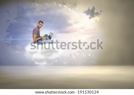 Man wearing glasses sitting using laptop and looking at camera against splash on wall revealing bright sky