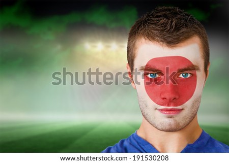 Composite image of japan football fan in face paint against football pitch under green sky and spotlights