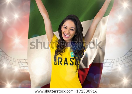 Excited football fan in brasil tshirt holding italy flag against large football stadium under cloudy blue sky