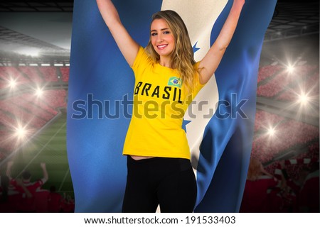 Excited football fan in brasil tshirt holding honduras flag against vast football stadium with fans in red