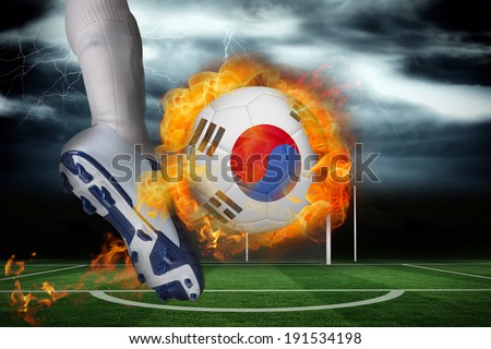 Football player kicking flaming south korea flag ball against football pitch under stormy sky