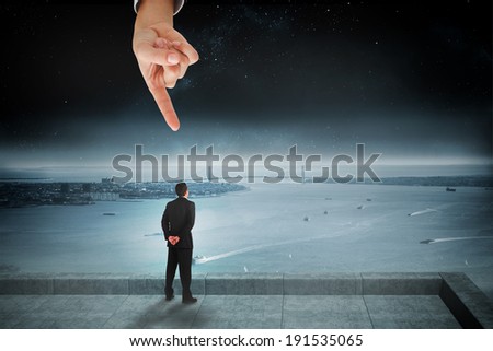 Giant hand pointing at businessman standing and looking against balcony overlooking coastline at night