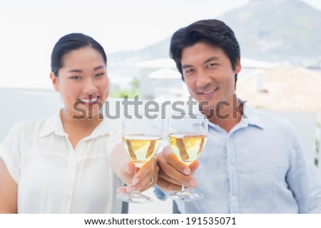 Happy couple having white wine outside on a balcony