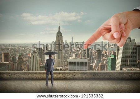 Giant hand pointing at businessman holding an umbrella against balcony overlooking city
