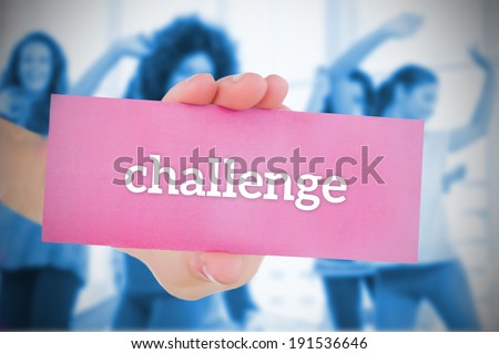 Woman holding pink card saying challenge against fitness class in gym