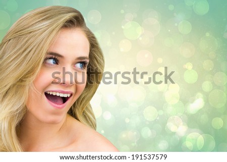Smiling blonde natural beauty against green abstract light spot design