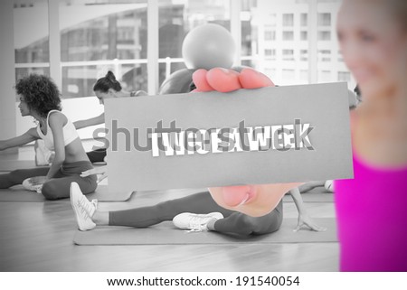 Fit blonde holding card saying twice a week against yoga class in gym