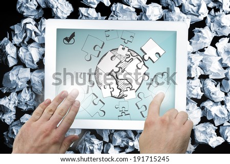 Composite image of hand touching tablet showing jigsaw and earth doodle