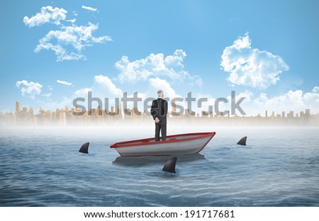 Rear view of mature businessman posing against sharks circling a small boat in the sea
