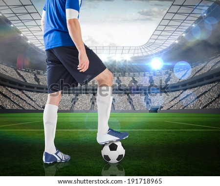 Composite image of football player standing with ball against large football stadium with lights