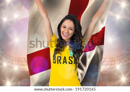 Excited football fan in brasil tshirt against holding england flag large football stadium under bright blue sky