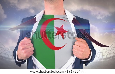 Businessman opening shirt to reveal algeria flag against large football stadium under cloudy blue sky