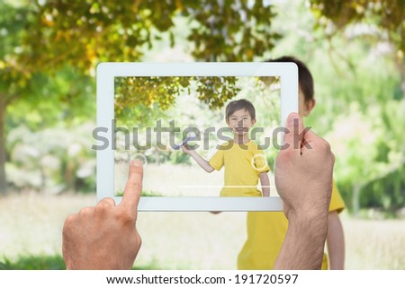 Hand holding tablet pc showing little boy holding paper airplane