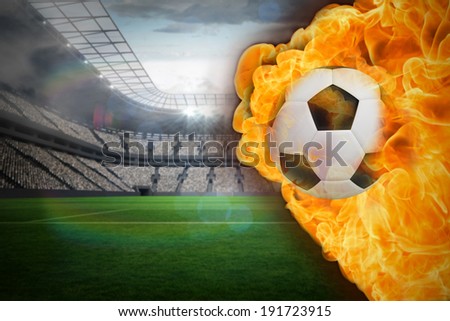 Composite image of fire surrounding football against large football stadium with lights