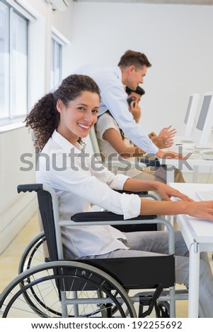 Casual businesswoman in wheelchair working at her desk in the office