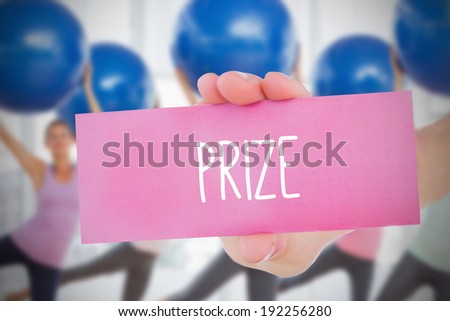 Woman holding pink card saying prize against fitness class in gym