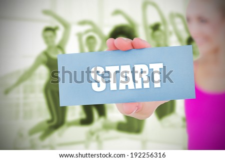 Fit blonde holding card saying start against class in gym