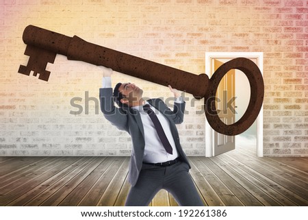 Unsmiling businessman carrying large key with arms raised against door opening showing blue sky